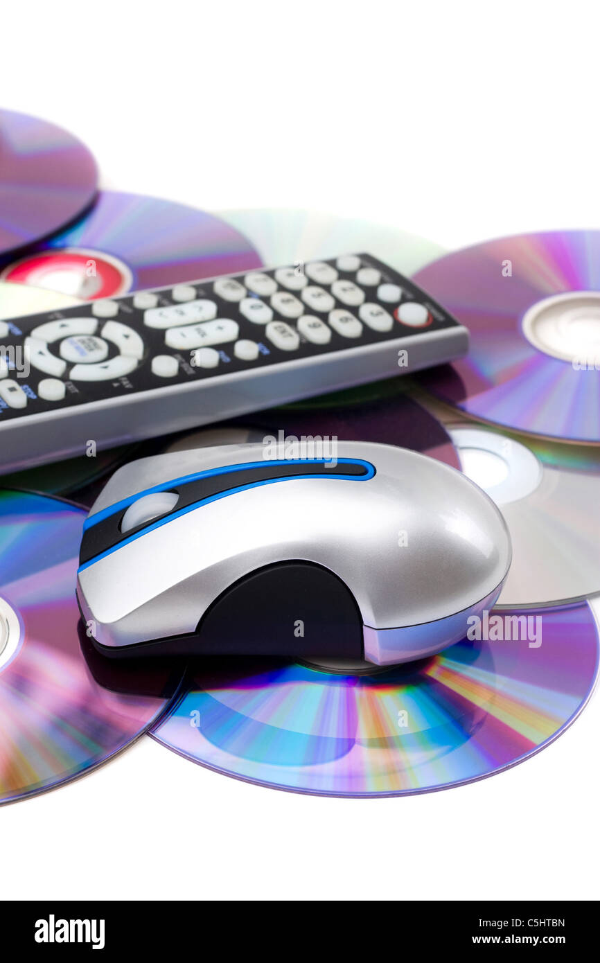 TV remote control and computer mouse on a pile of scattered dvd disks isolated over white. Stock Photo
