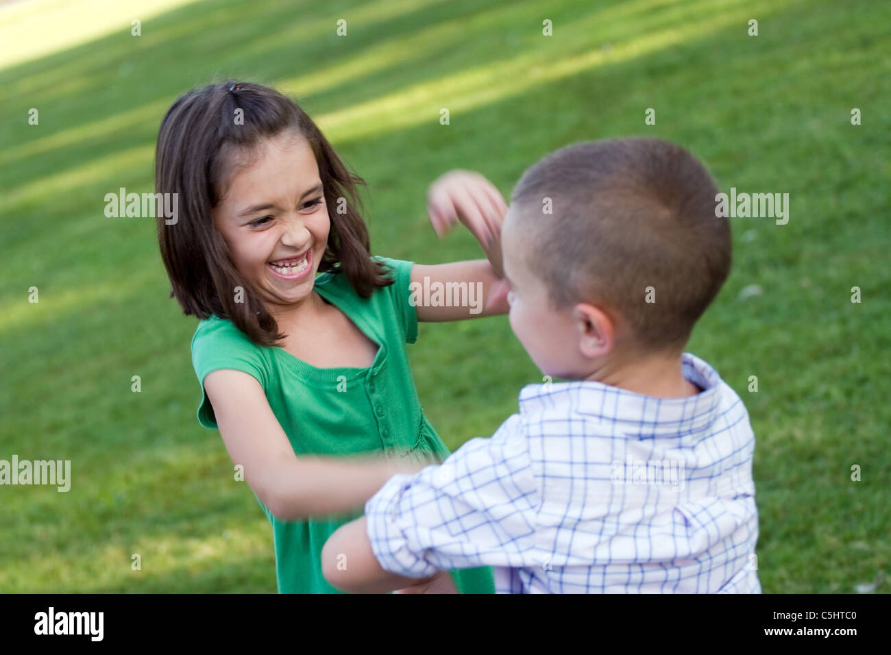 Two young sibling playfully hitting each other and rough housing. Slight motion blur with sharp focus on the girls face. Stock Photo
