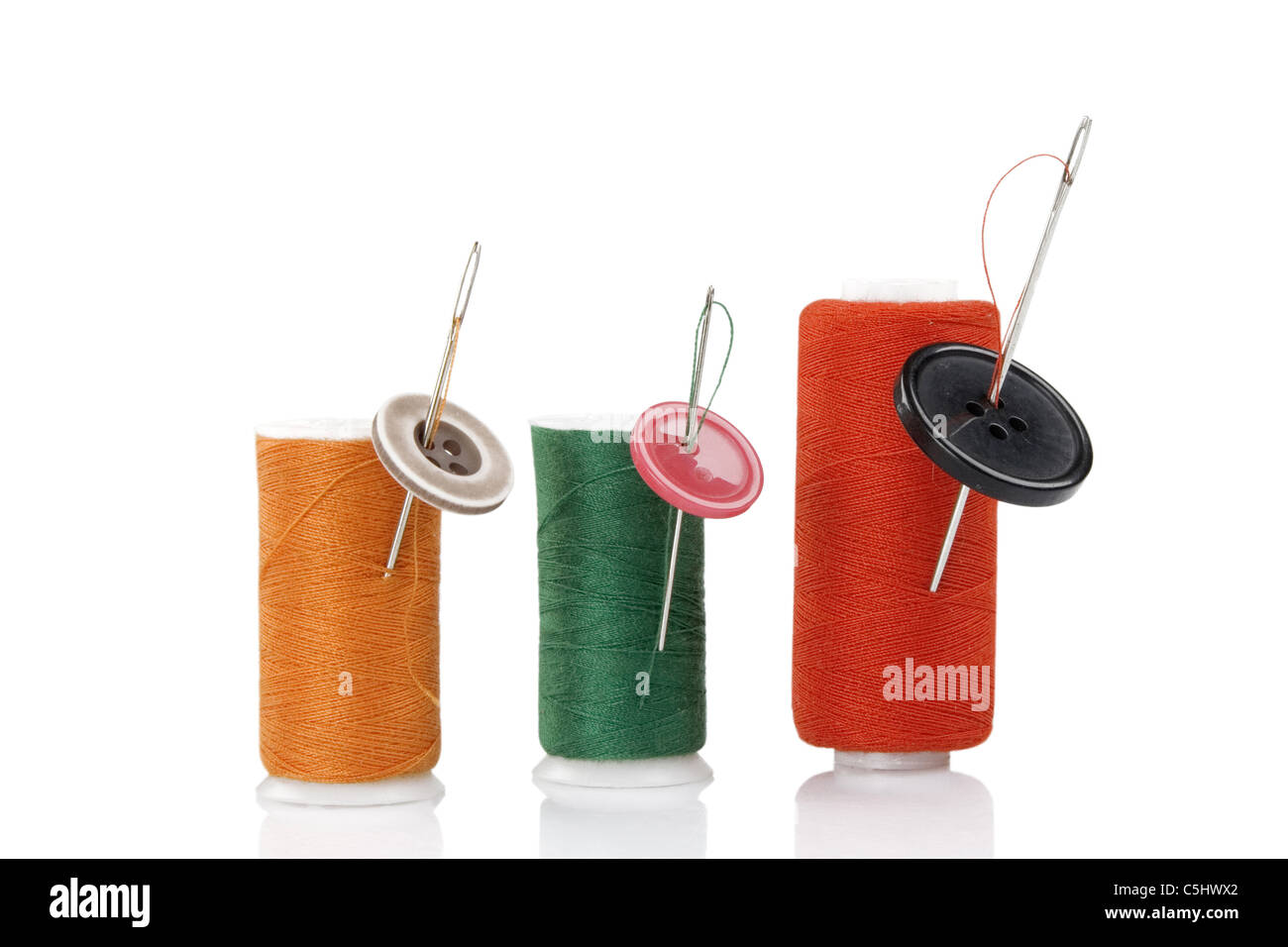 three colored spool with needles and buttons Stock Photo