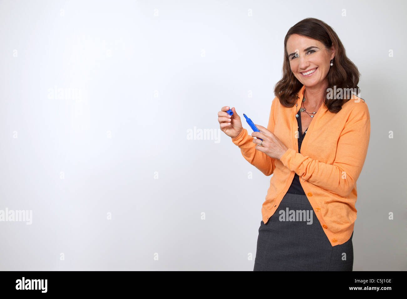 Woman at white board with blue marker in hand. Stock Photo