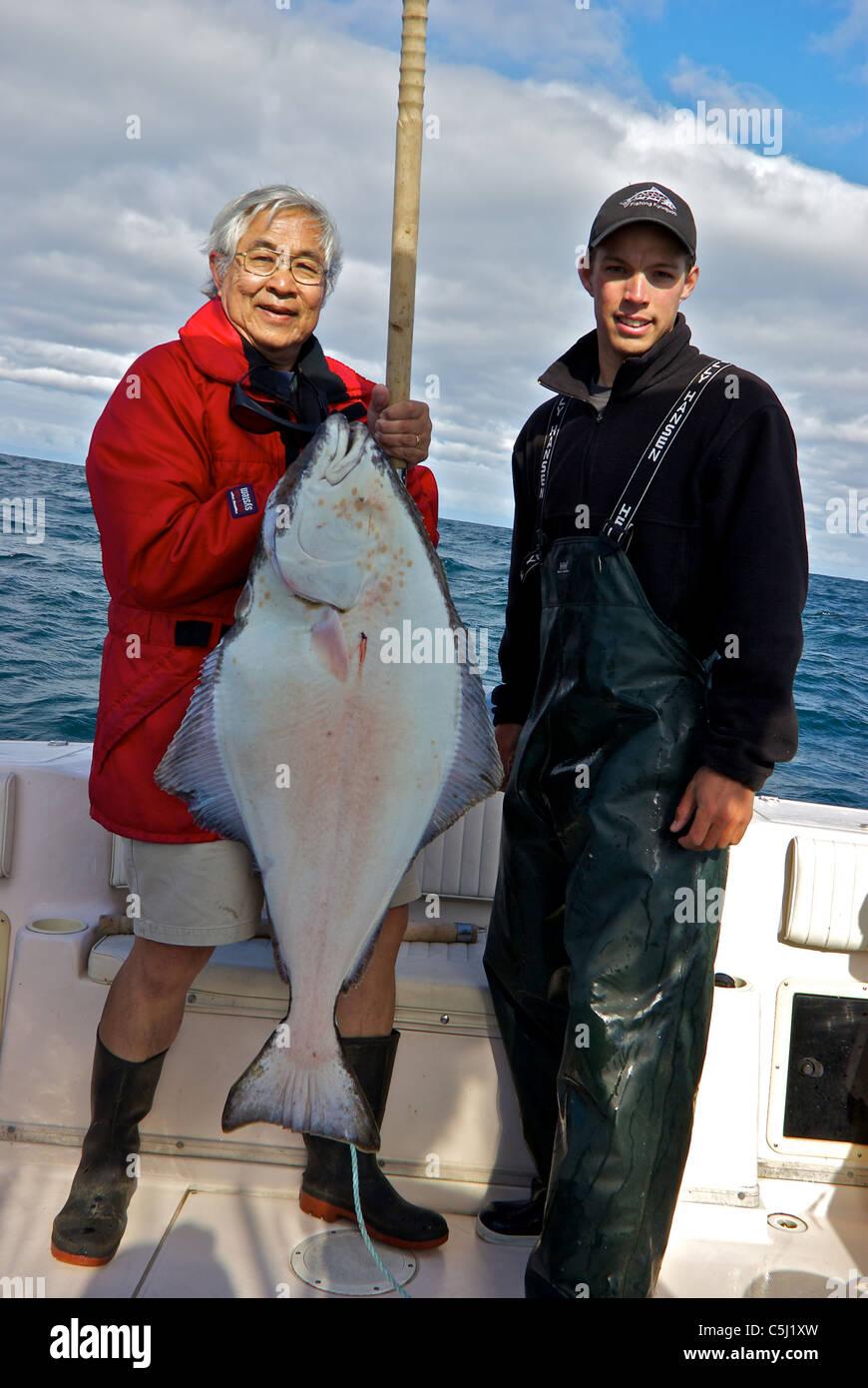 Sport fishing guide charter and guest holding halibut rough seas open Pacific Ocean Kyuquot Sound BC Stock Photo