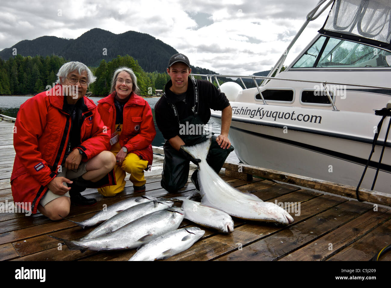 Sport fishing guide charter guests admiring catch of Chinook and coho salmon halibut Kyuquot Sound BC Stock Photo