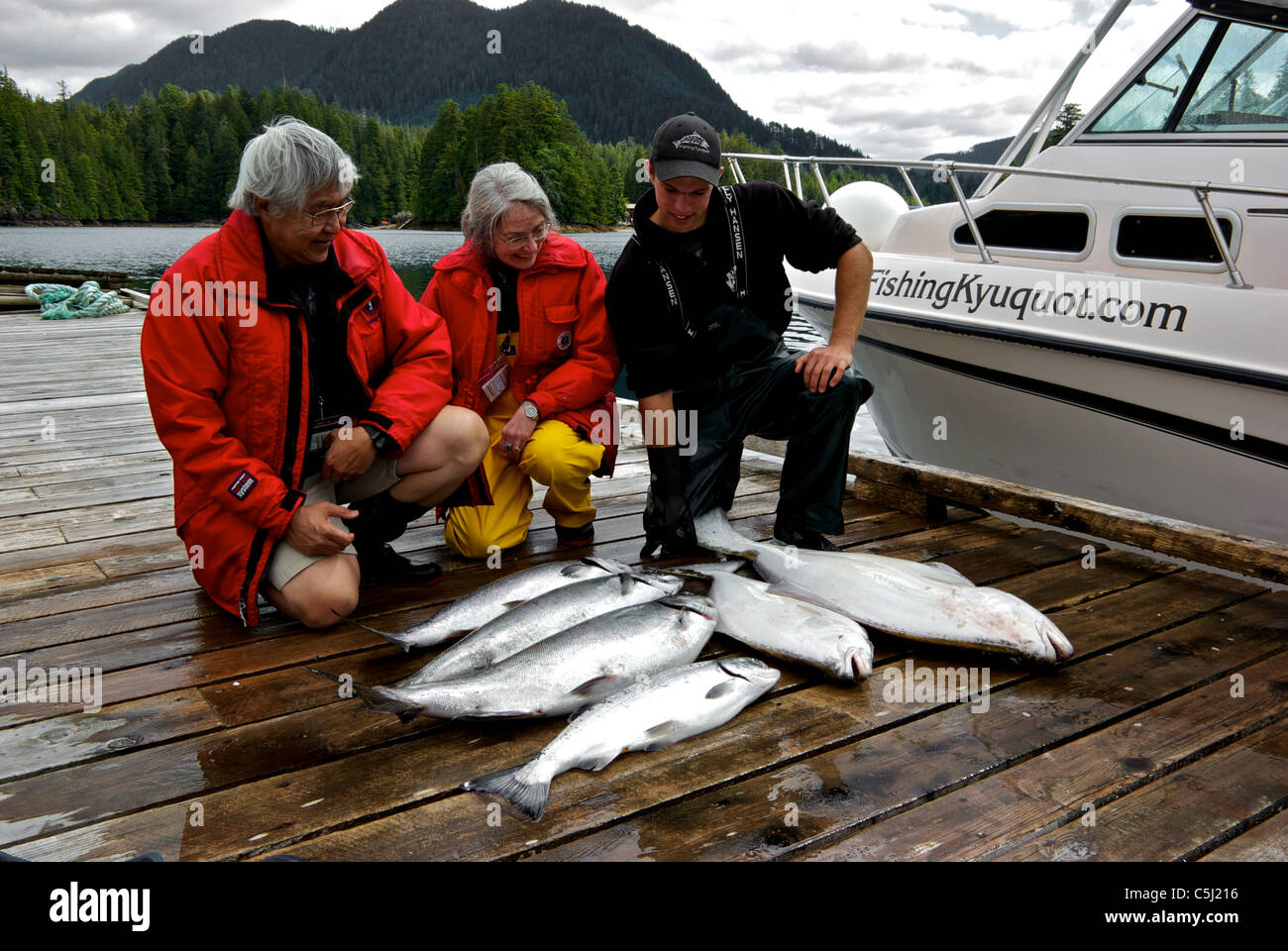 Sport fishing guide charter guests admiring catch of Chinook and coho salmon halibut Kyuquot Sound BC Stock Photo