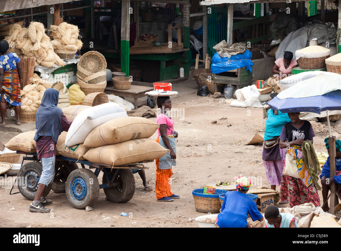 People unloading sacks of coco beans from cart at Agbogbloshie Market