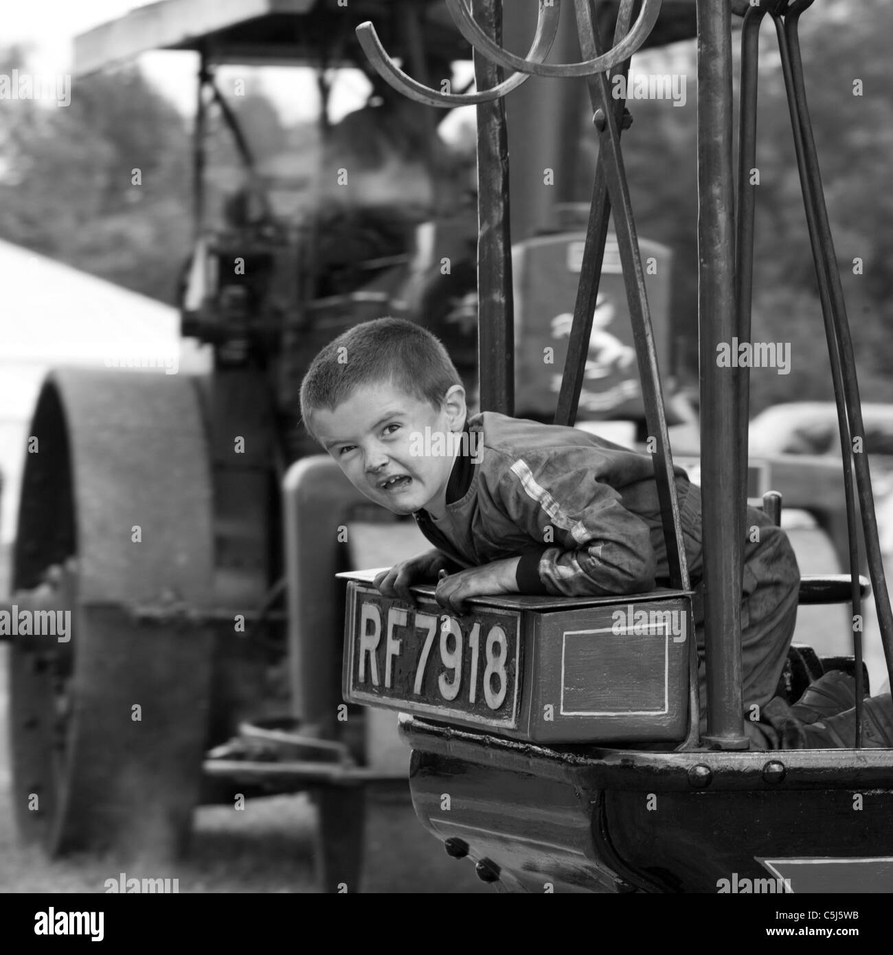 Boy making a face on traction engine at Woodcote Vintage Steam Rally, Woodcote, Reading, Berkshire, England Stock Photo