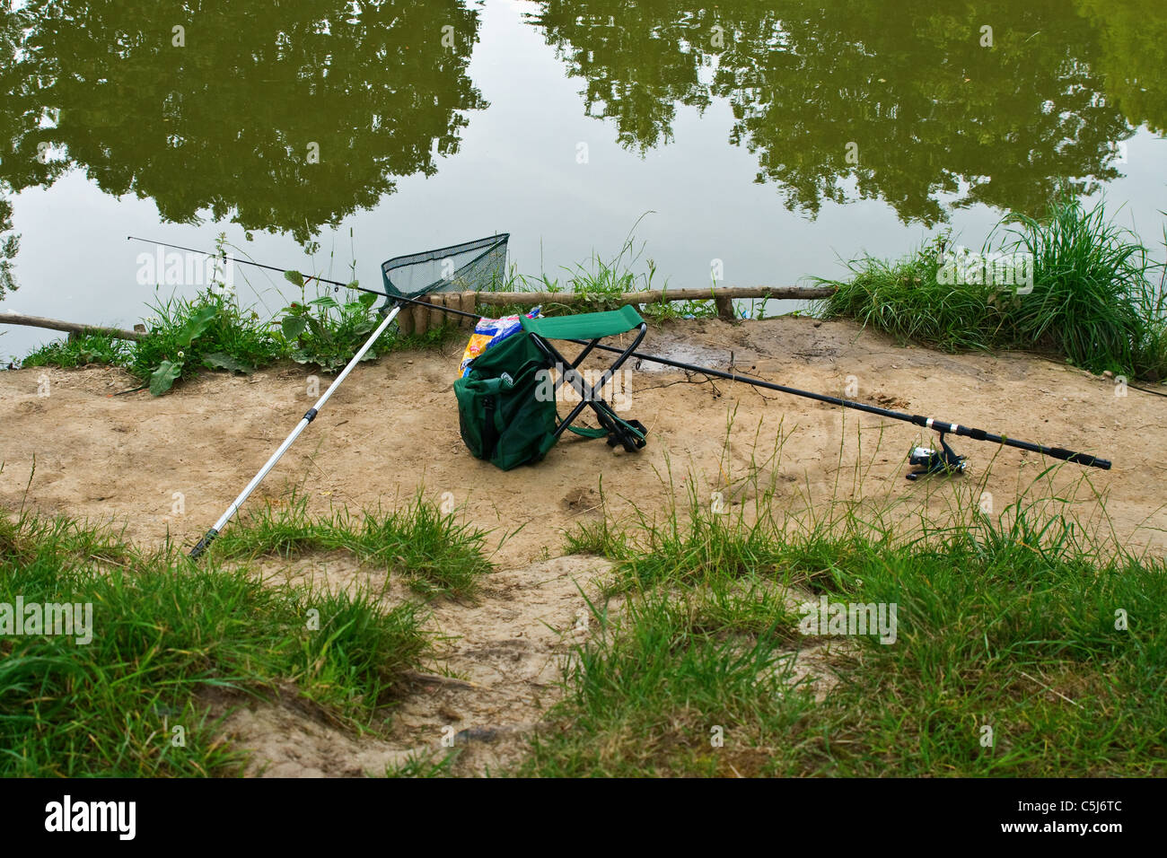 Fresh water fishing tackle on the bank, fishing rod, fishing bag and fishing net Stock Photo
