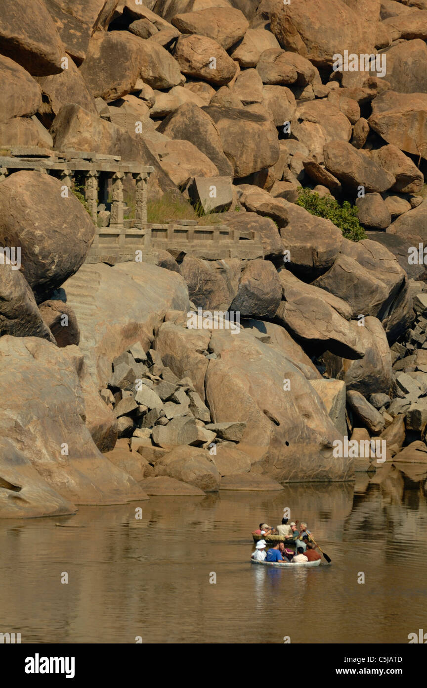 Tourists floating down the Tungabhadra River in traditional nut shell style boats. India, Karnataka, Hampi. Stock Photo