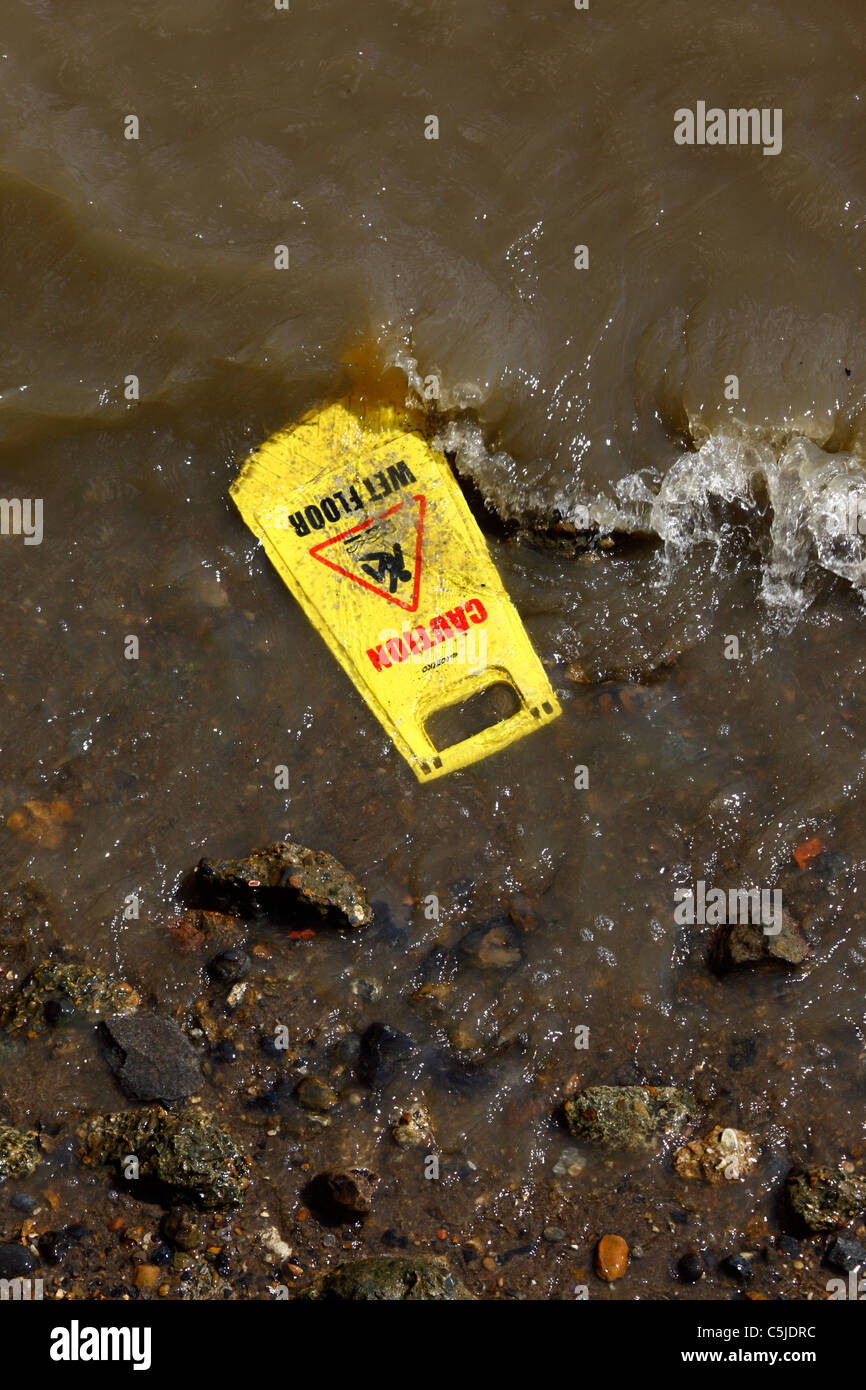 Caution Wet Floor sign being washed up by River Thames, London, England Stock Photo