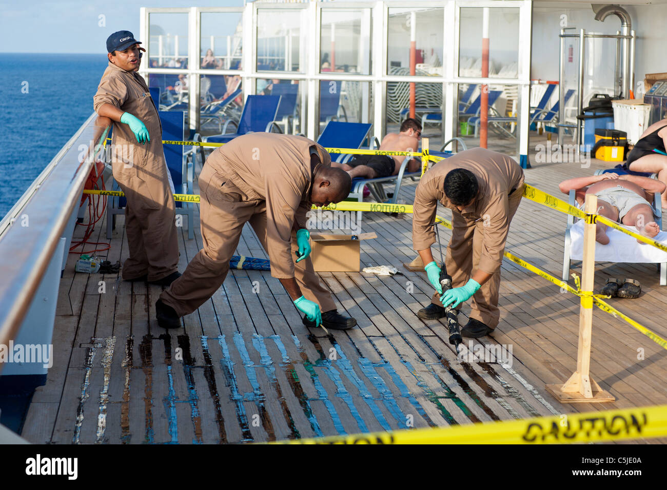 Ship workers apply sealer on wooden deck of Carnival's Triumph cruise