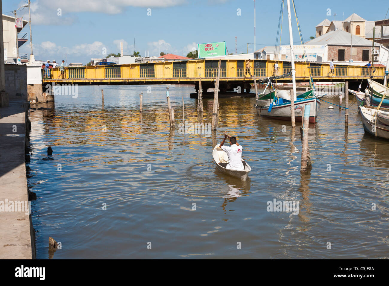 Man rowing canoe type boat on Haulover Creek near swing bridge in Belize City, Belize Stock Photo