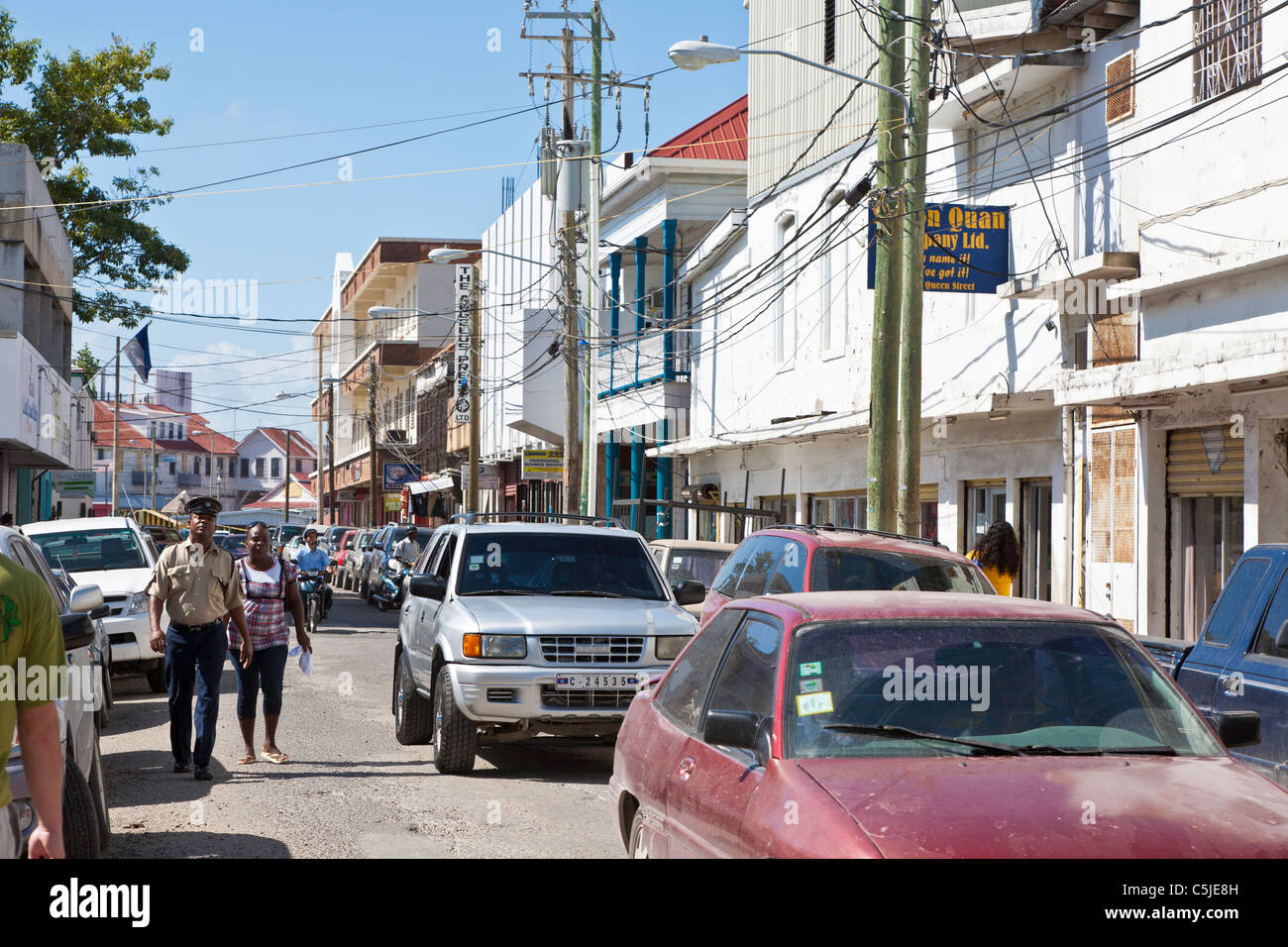 Policeman walking with woman on congested street in downtown Belize City, Belize Stock Photo