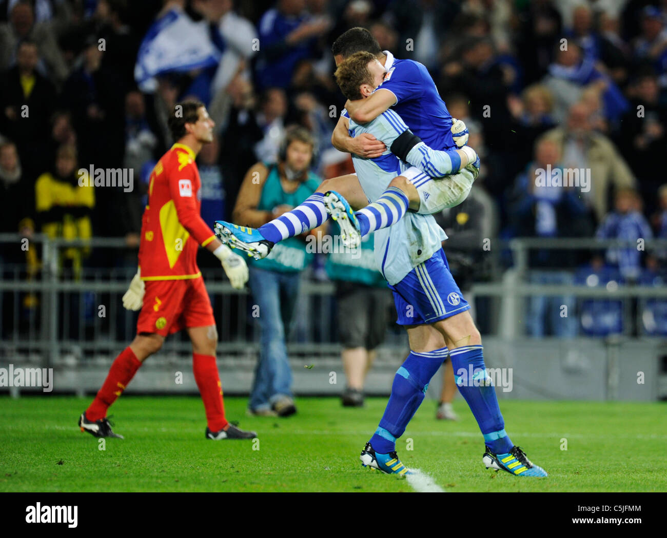 Schalke 04 player Kyriakos Papadopoulos jumps on to goalkeeper Ralf Faehrmann in celebration as Dortmund Goalkeeper Roman Weiden Stock Photo