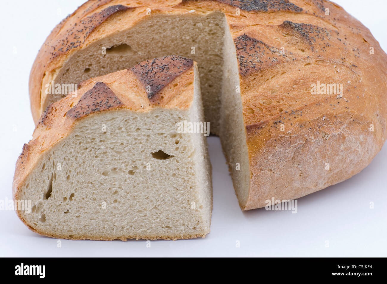 Cut round loaf of bread with poppyseed on white background Stock Photo