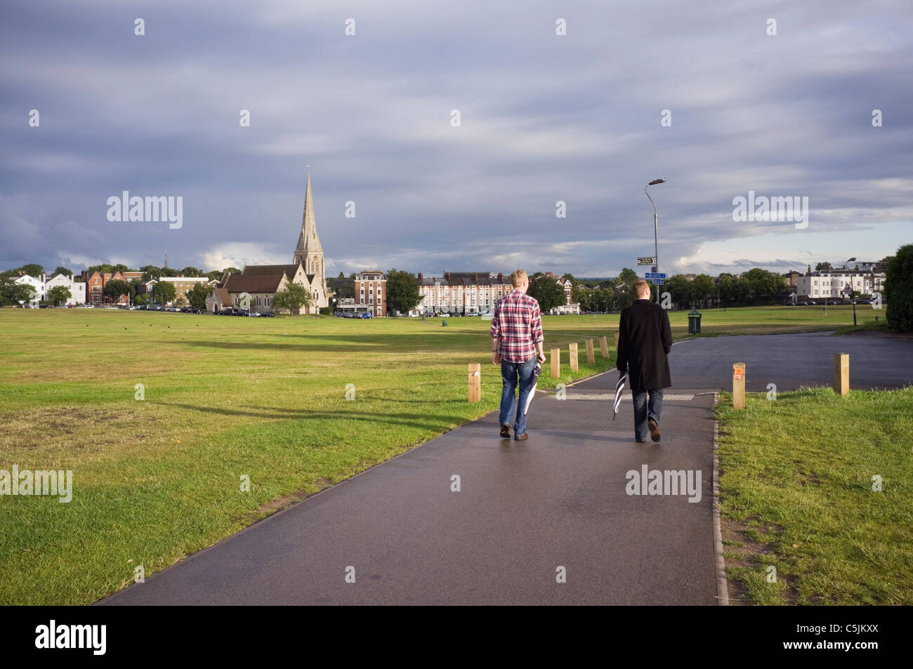 Two young men walking across the heath to the village. Blackheath, London, England, UK, Britain. Stock Photo