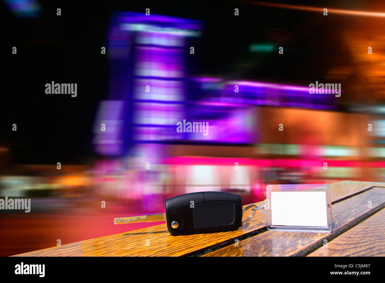 Car rental keys on wood table with blank paper in night downtown blurred lights Stock Photo