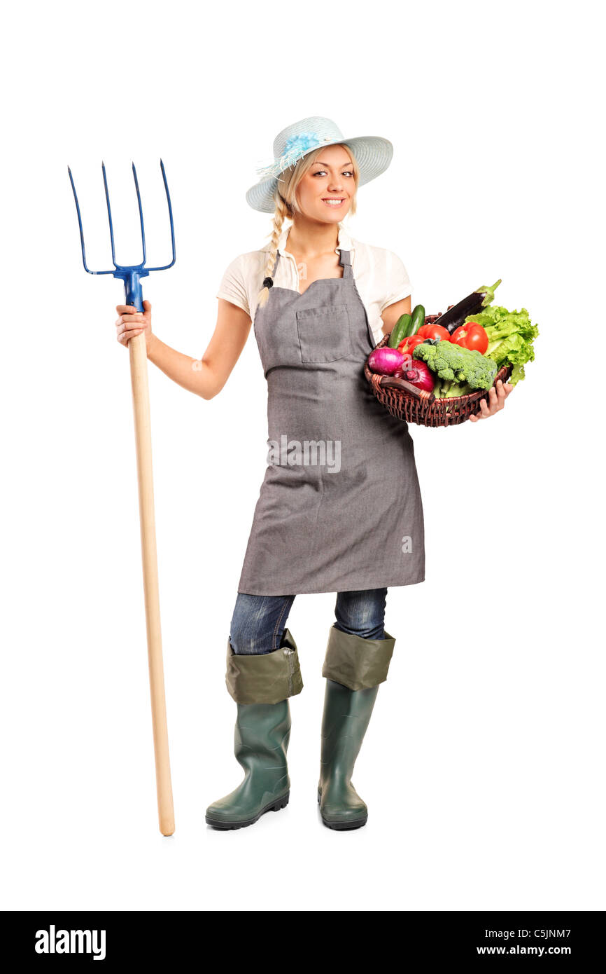 Full length portrait of a female farmer holding a pitchfork and basket ...