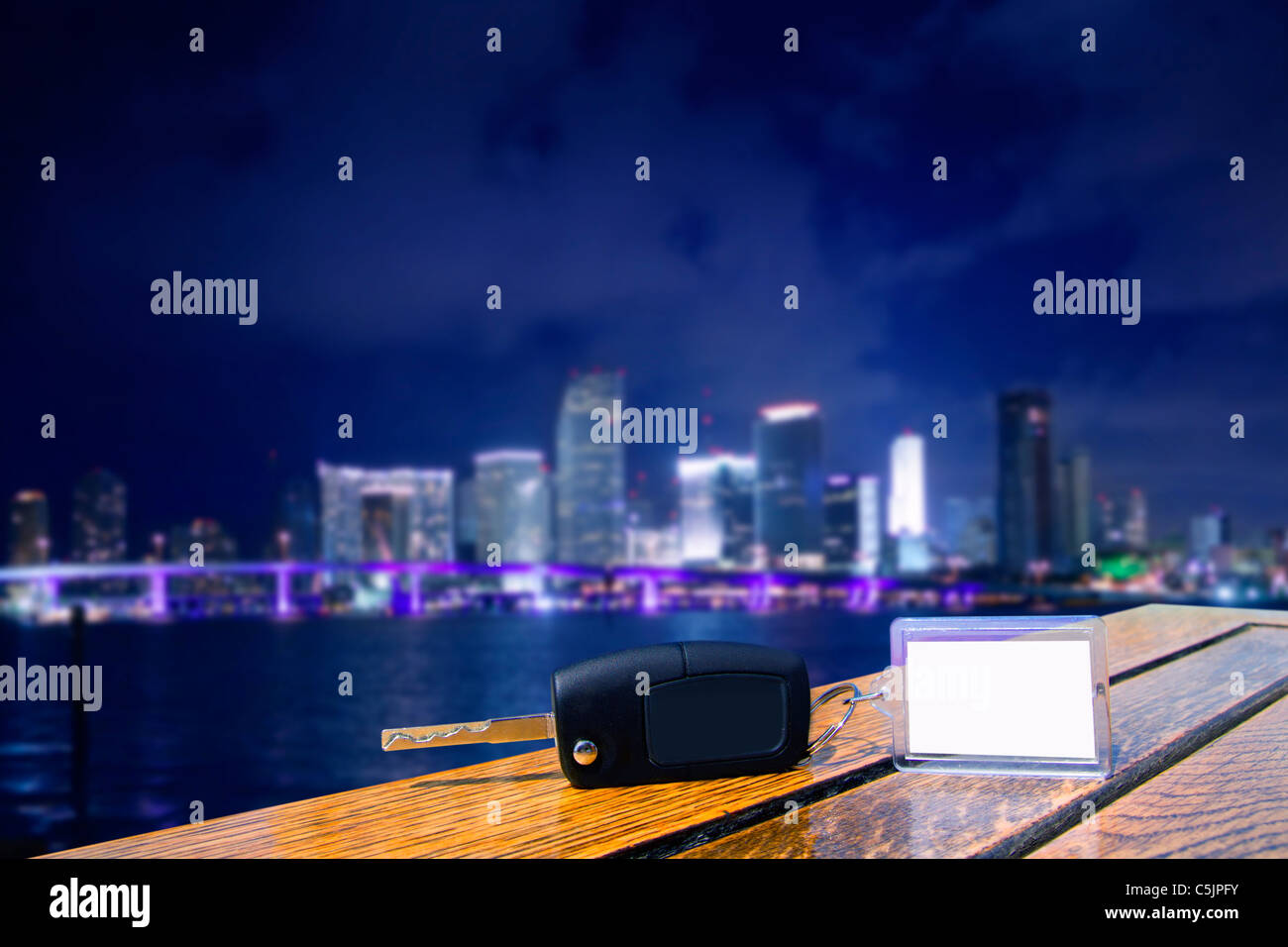 Car rental keys on wood table with blank paper in Miami night downtown Stock Photo