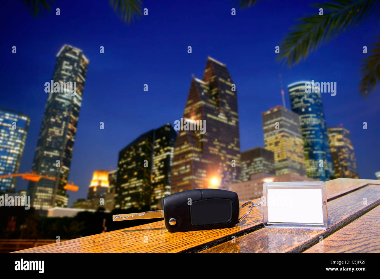 Car rental keys on wood table with blank paper in Houston night downtown Stock Photo