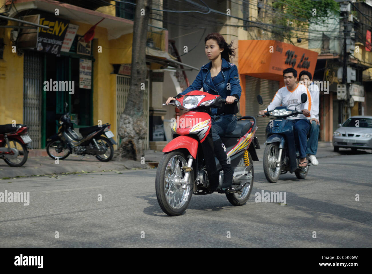 Asia, Vietnam, Hanoi. Hanoi old quarter. Young vietnamese woman riding a small motorbike through Hanoi. Stock Photo