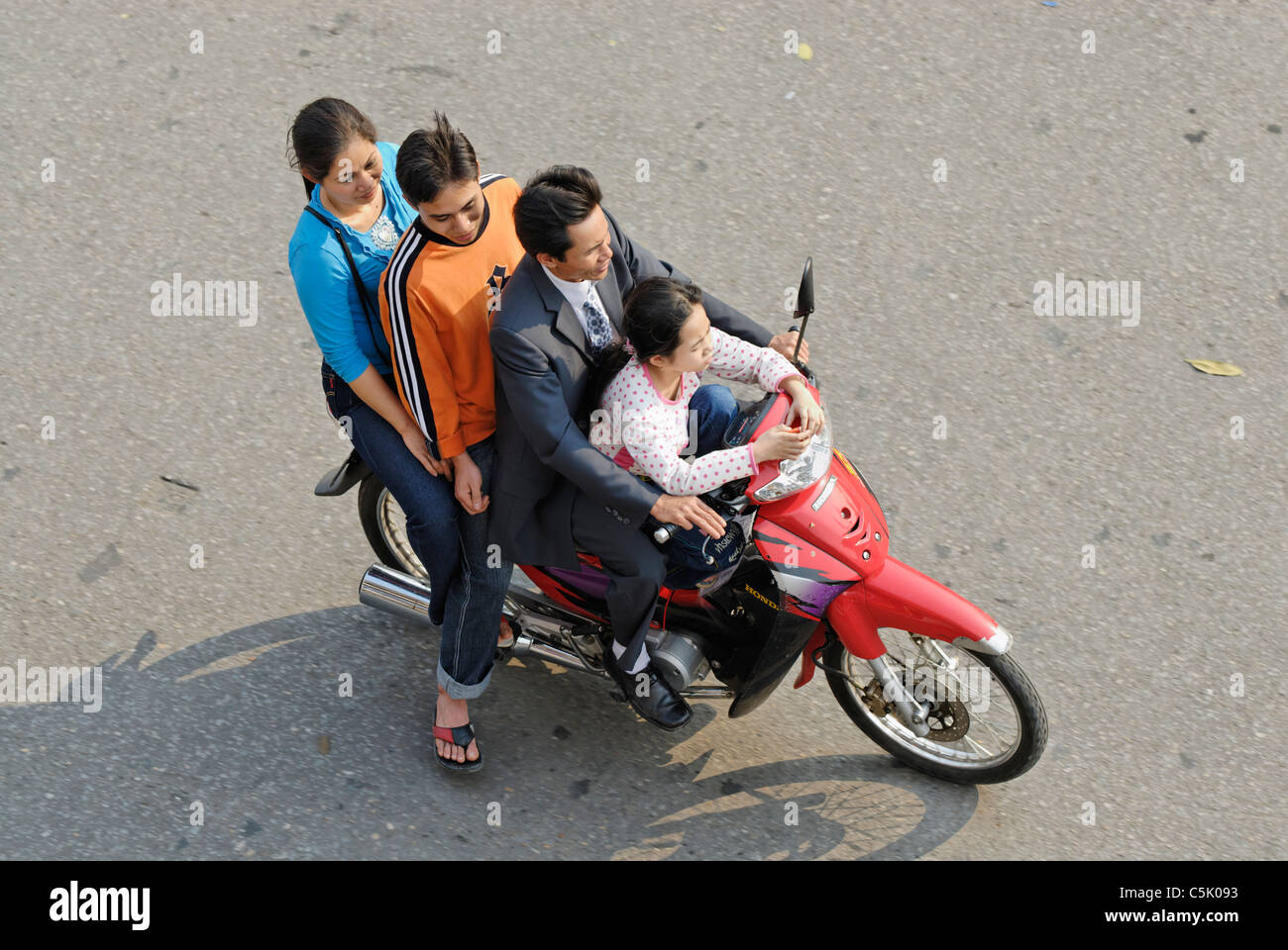 Asia, Vietnam, Hanoi. Hanoi old quarter. Vietnamese family of four riding on a motorbike through Hanoi. Stock Photo