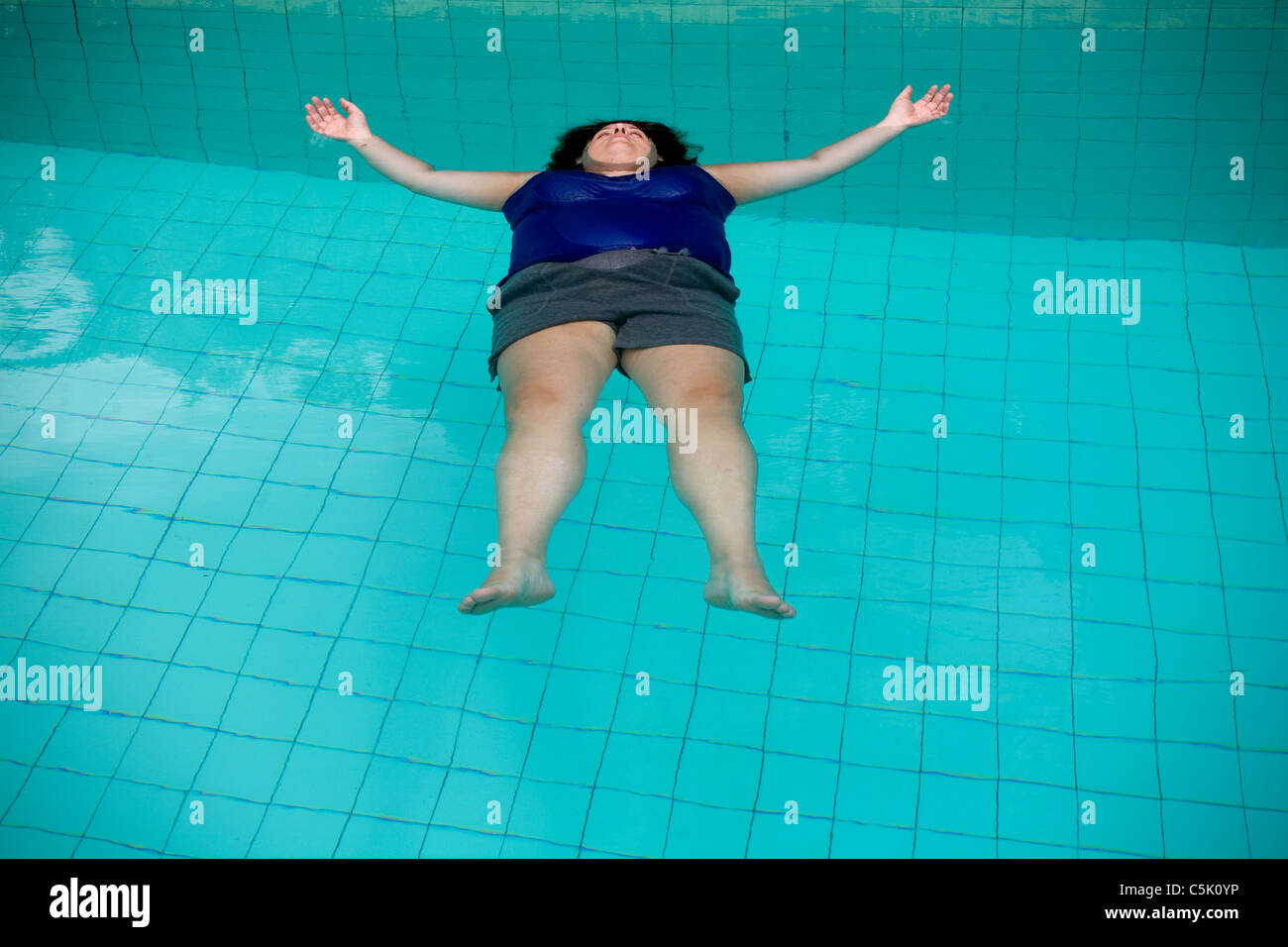 Woman floating in the water of a swimming pool Stock Photo