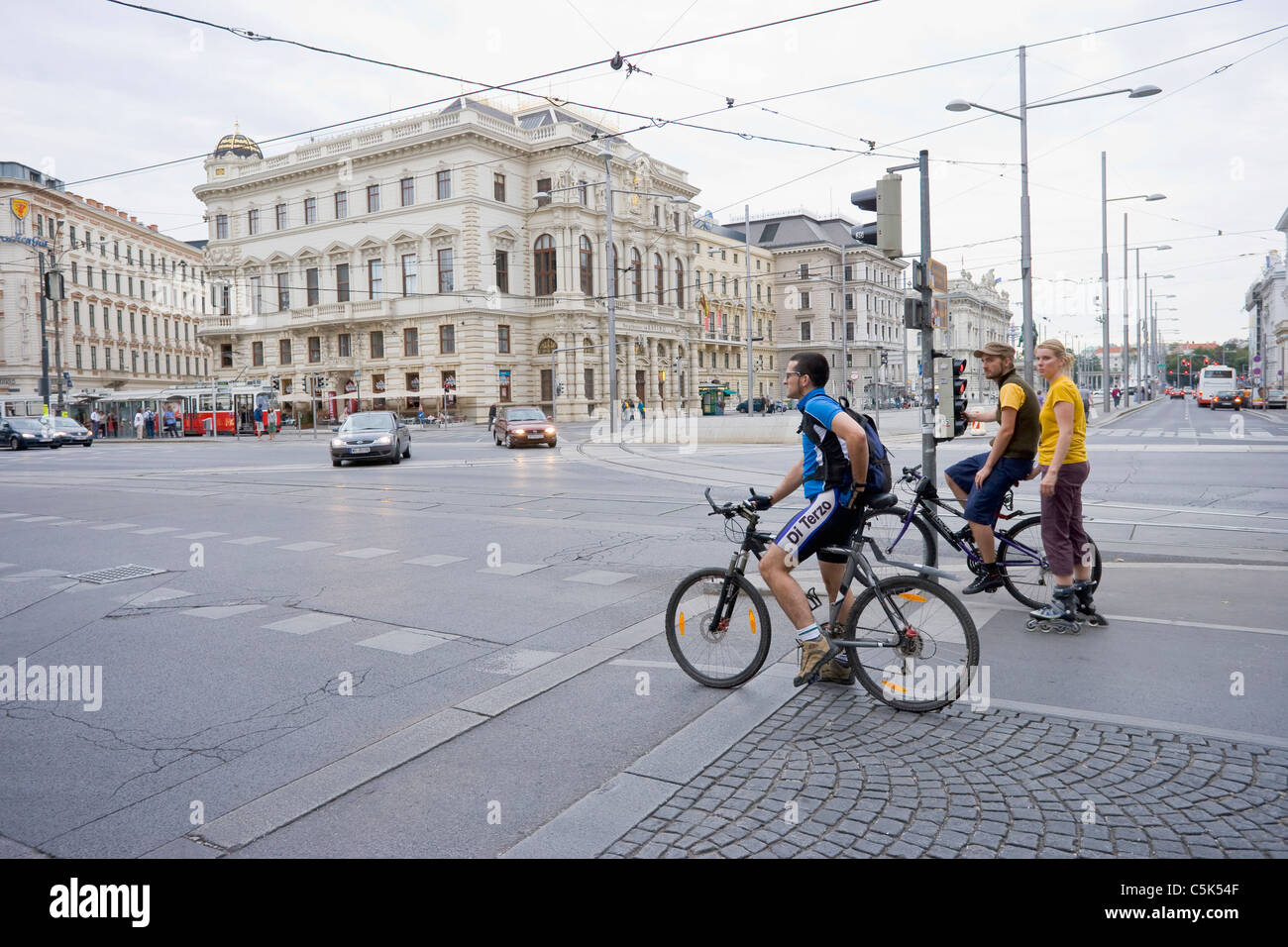 Male cyclists and female rollerblader waiting at red light, Vienna, Austria Stock Photo