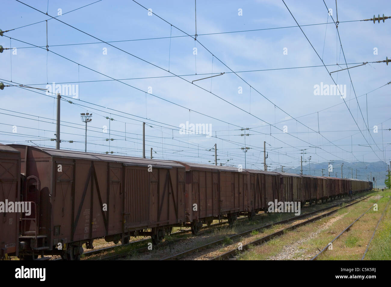 Freight train and power lines as seen from inside the railroad station, Fevzipasa, near Gaziantep / Antep, Turkey Stock Photo