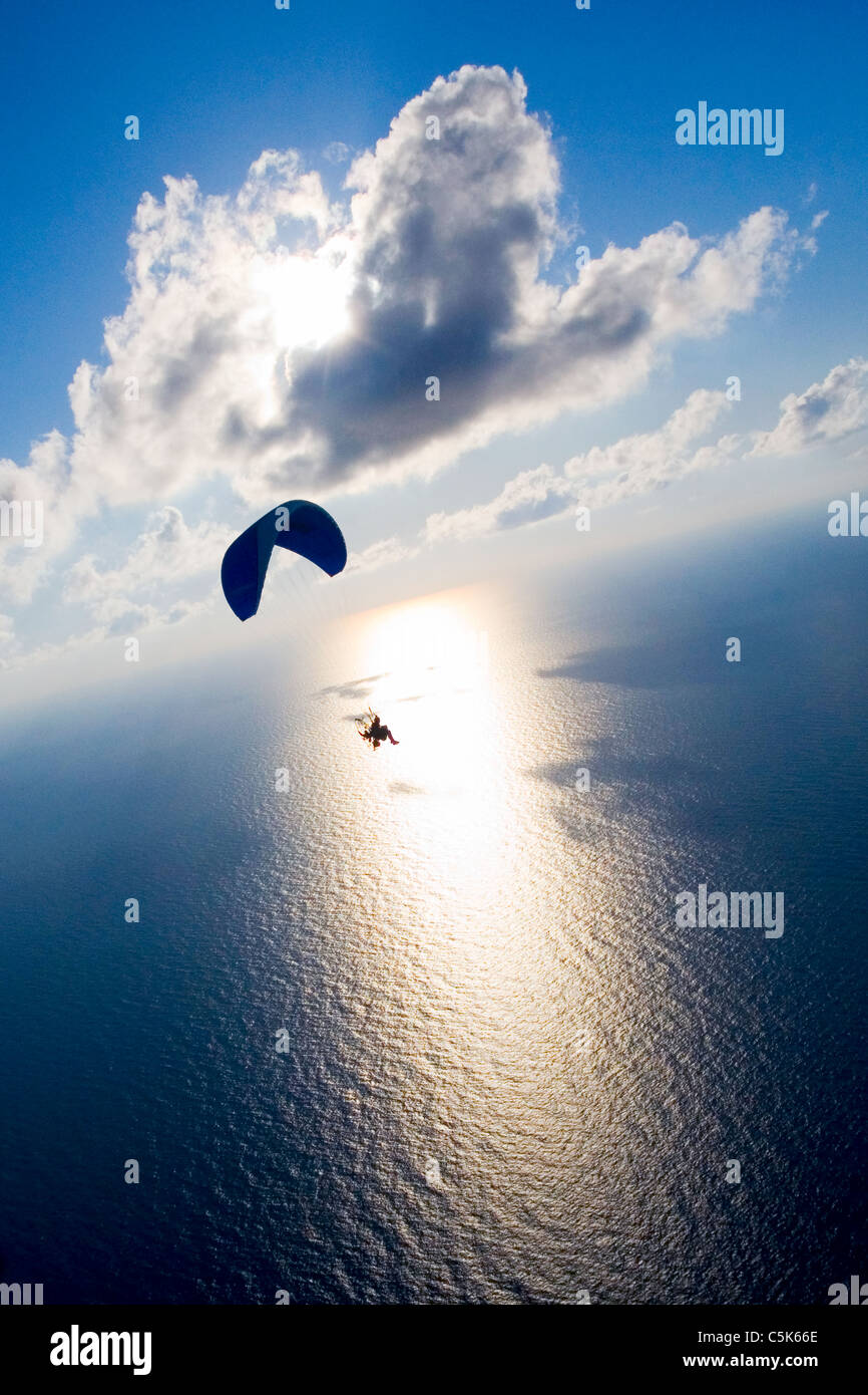 Powered paraglider flying over the sea with blue sky, clouds and shining sun Stock Photo Alamy