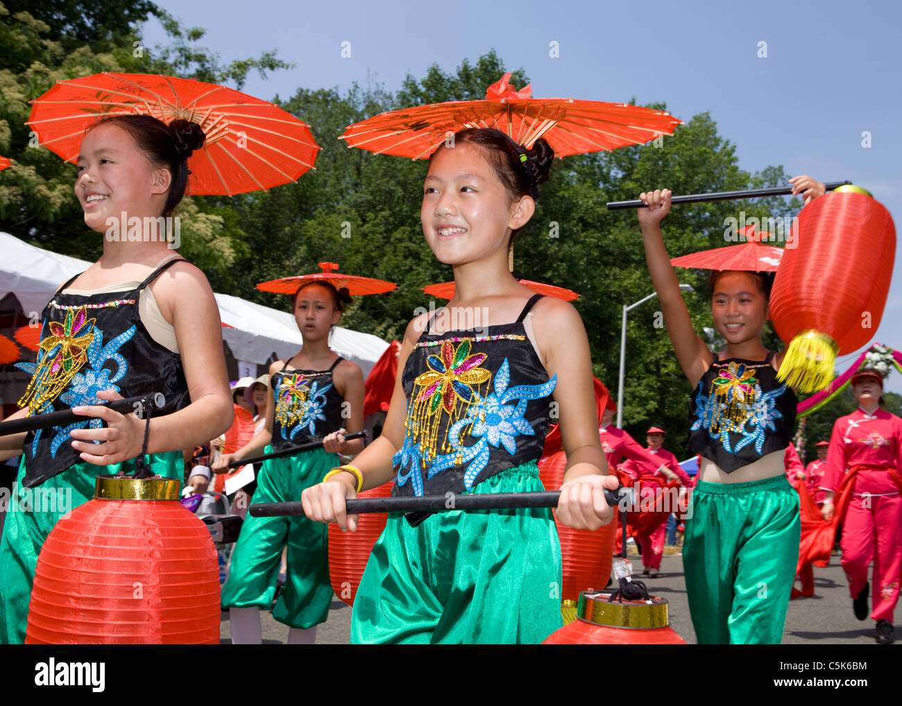Young Chinese girls carrying paper lanterns and wearing paper parasols in a parade Stock Photo