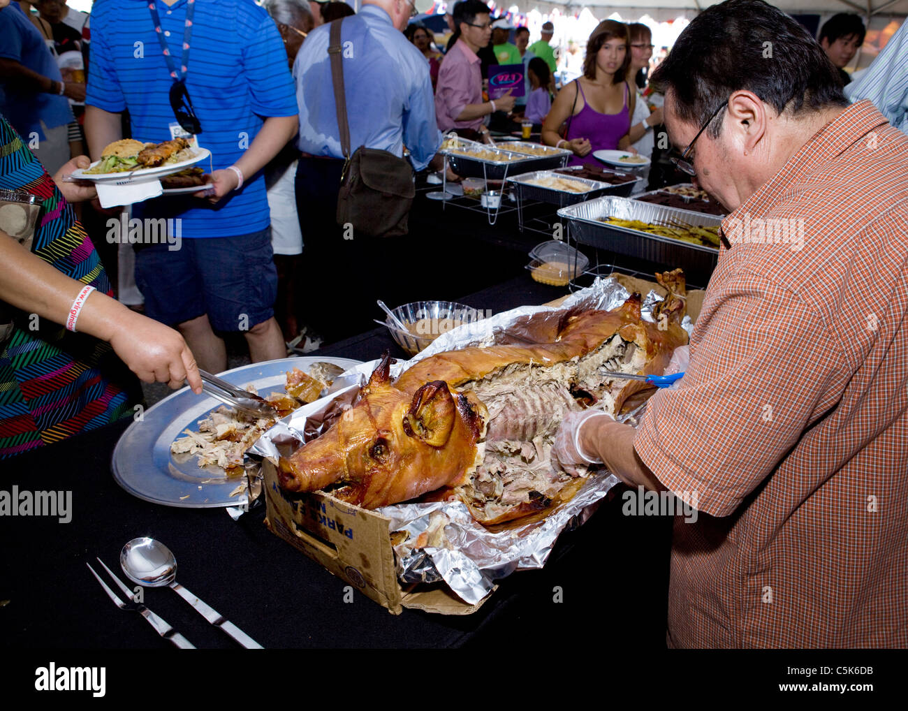 A man carving a whole roast suckling pig Stock Photo