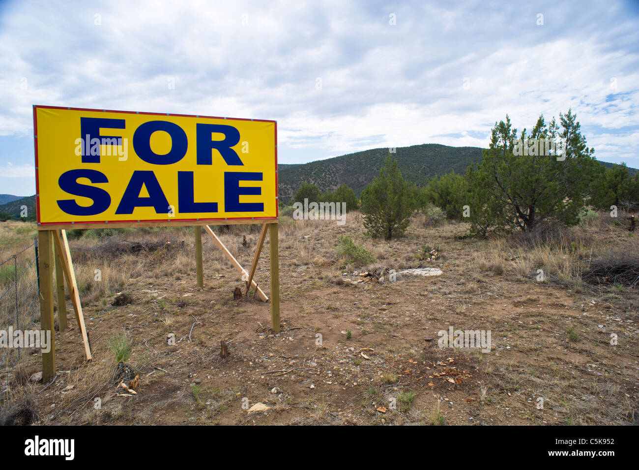 A large FOR SALE sign dominates the landscape in Lincoln County, New Mexico. Stock Photo
