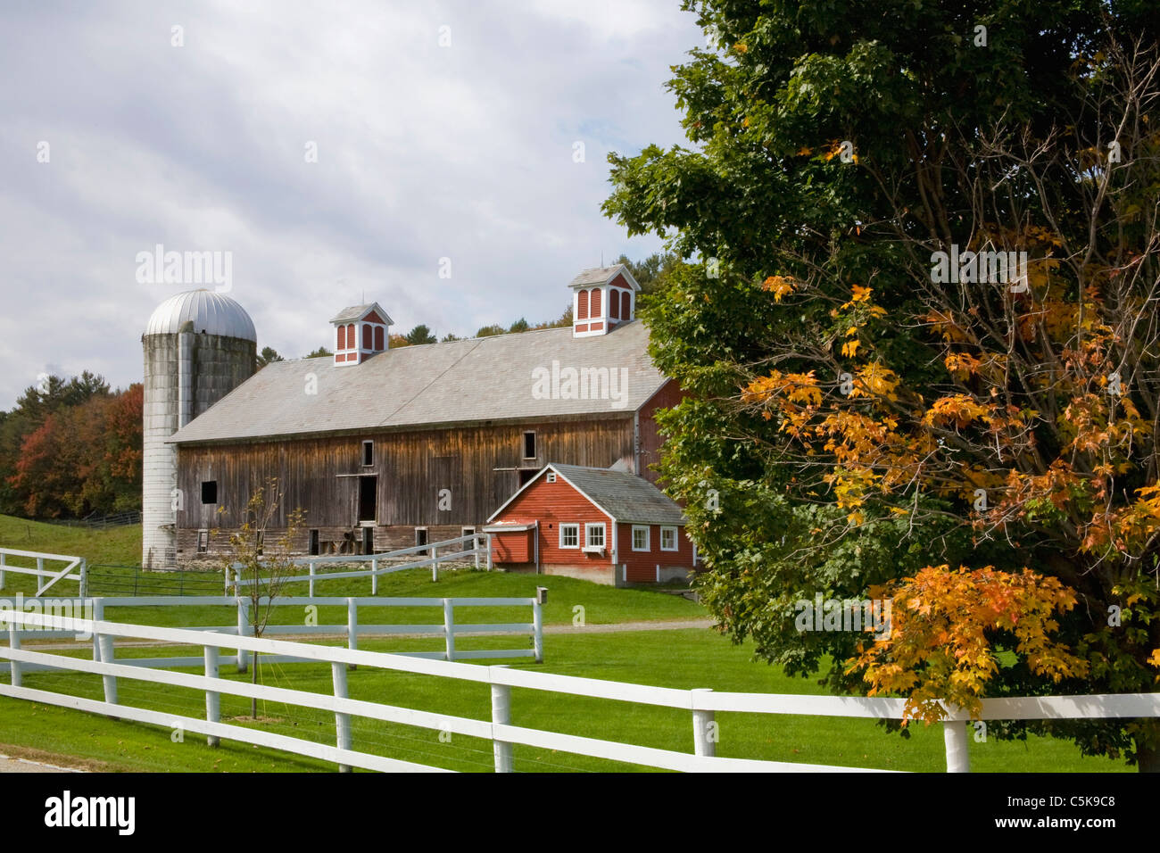 Old barn and silo in Fall with white fence. Stock Photo