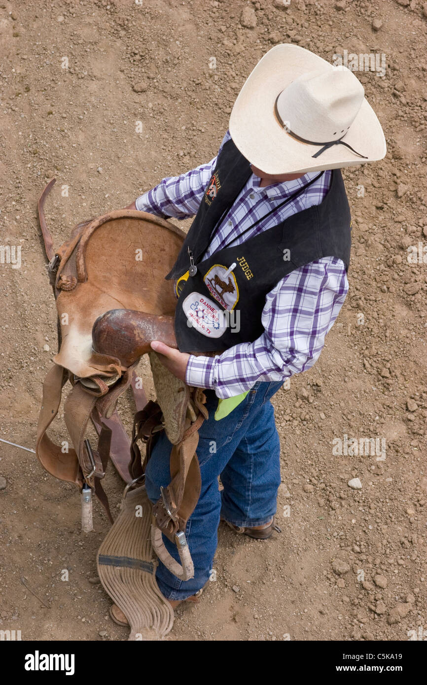 A rodeo judge carries a saddle to a waiting horse Stock Photo Alamy