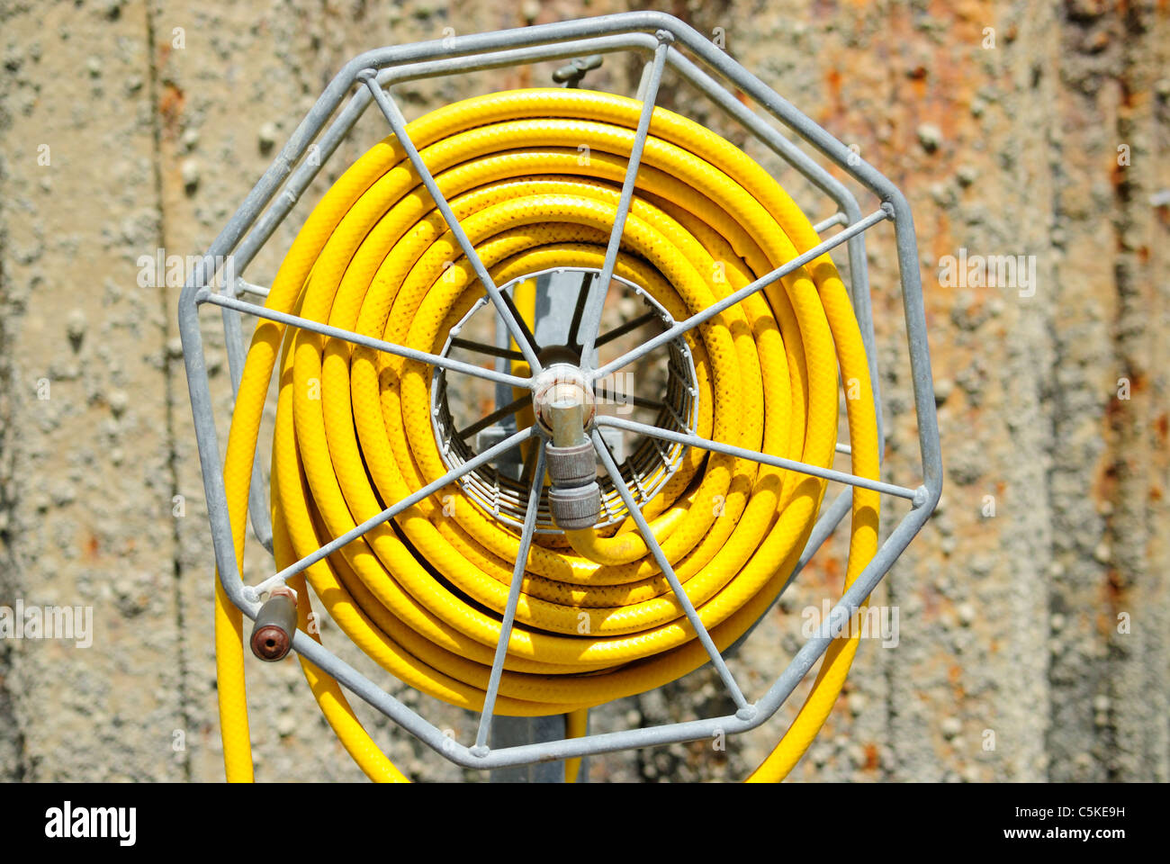 Yellow Hose and hose reel in natural garden setting Stock Photo - Alamy