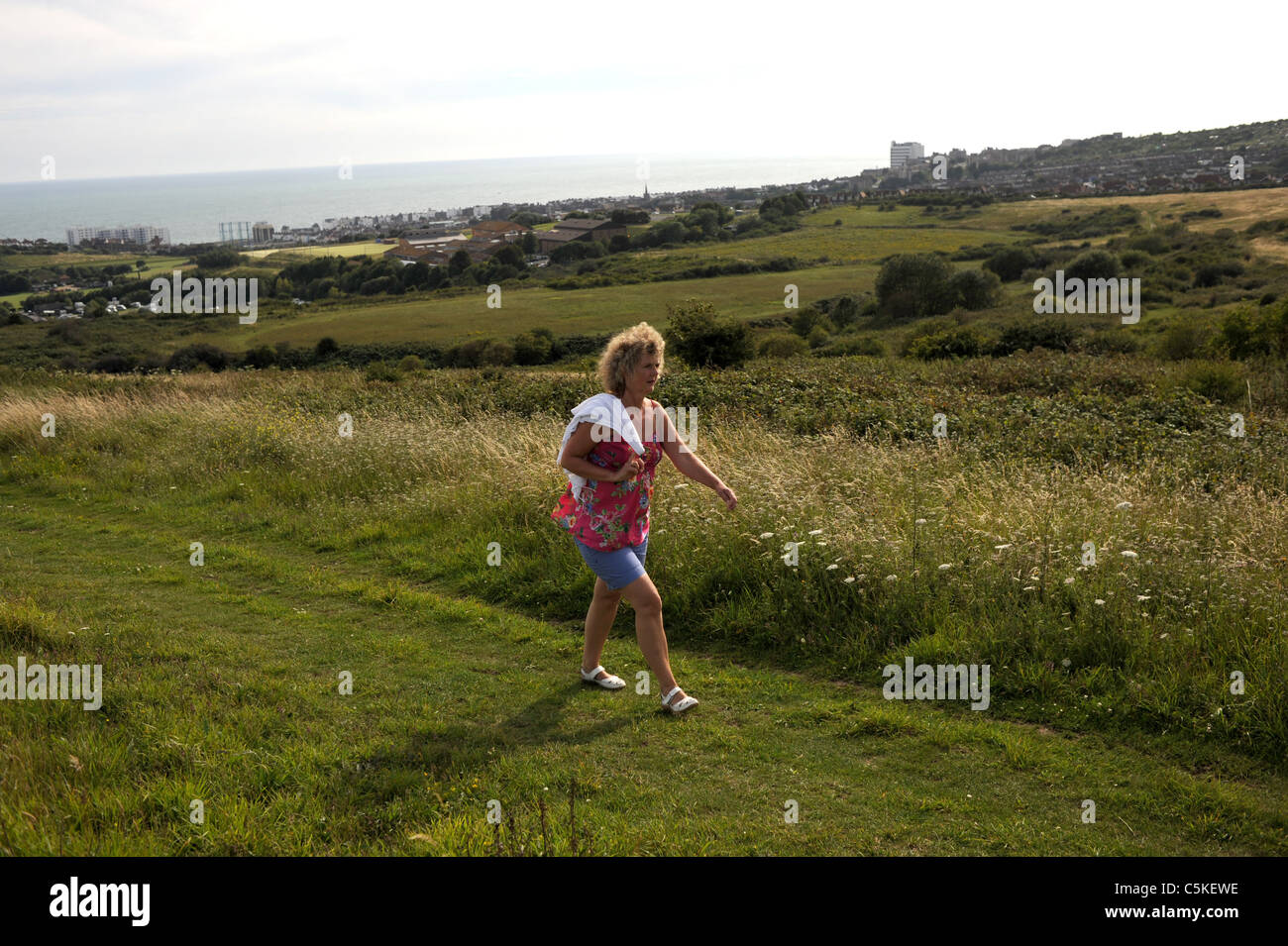 Middle aged woman walking in Wild flower meadow on the downs at Sheepcote Valley near Brighton city centre UK Stock Photo
