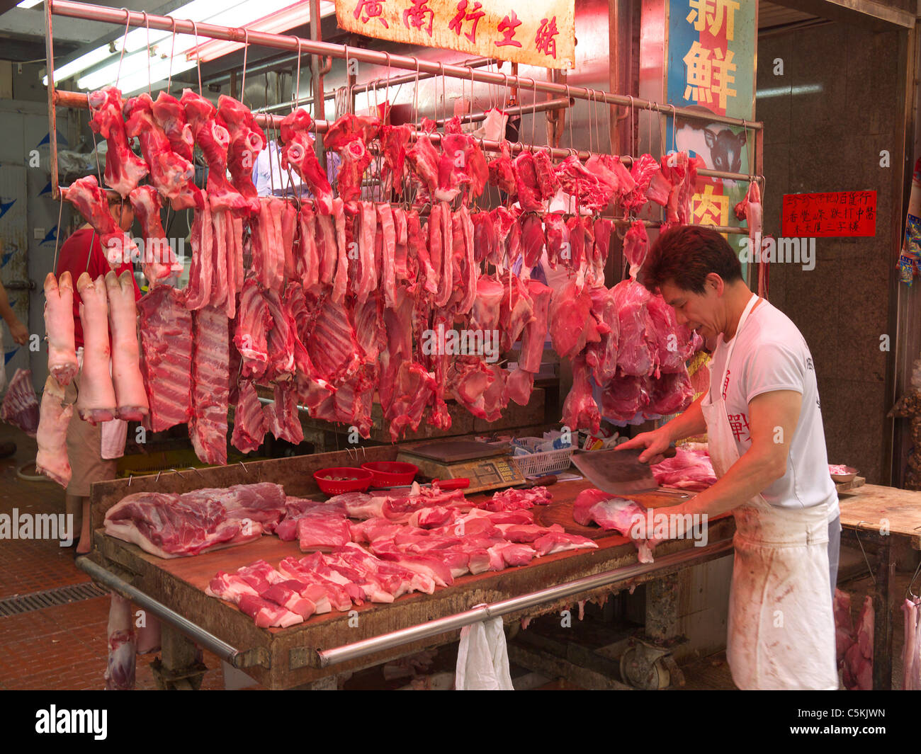 Chinese butcher at work preparing meat for sale at a market in ...