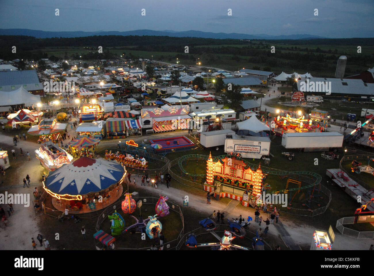 People walk across the midway of the Addison County Field Days Fair in