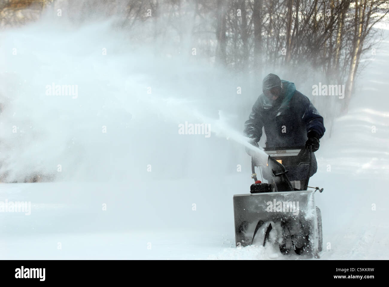 A man runs his snow blower as he clears his driveway of snow after a