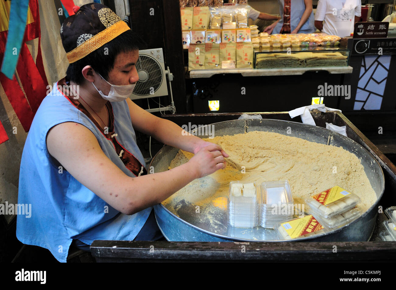 A young man making candy in front of a shop. Chengdu, Sichuan, China. Stock Photo