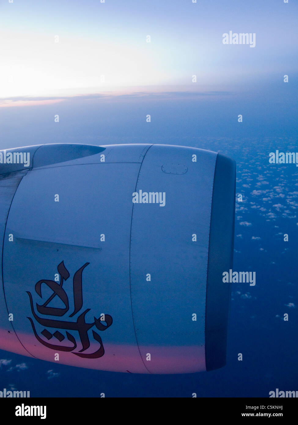 Port engine of a Boeing 777 jet airliner with logo of Emirates Airlines in flight at dusk Stock Photo