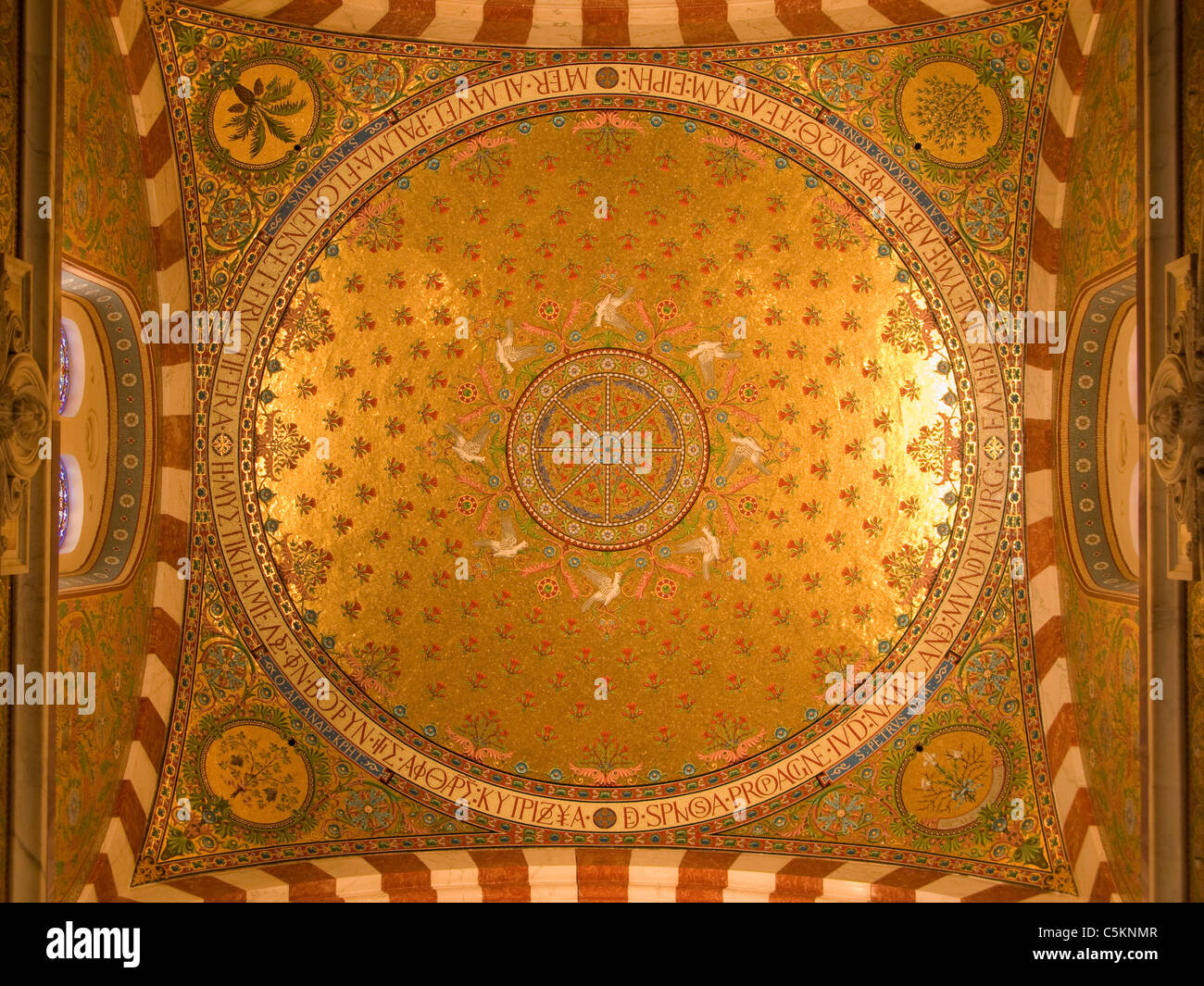Inside of the main dome at Notre-Dame-de-la-Garde, Marseille, France, with gold tiled mosaic and Greek and Latin inscriptions Stock Photo