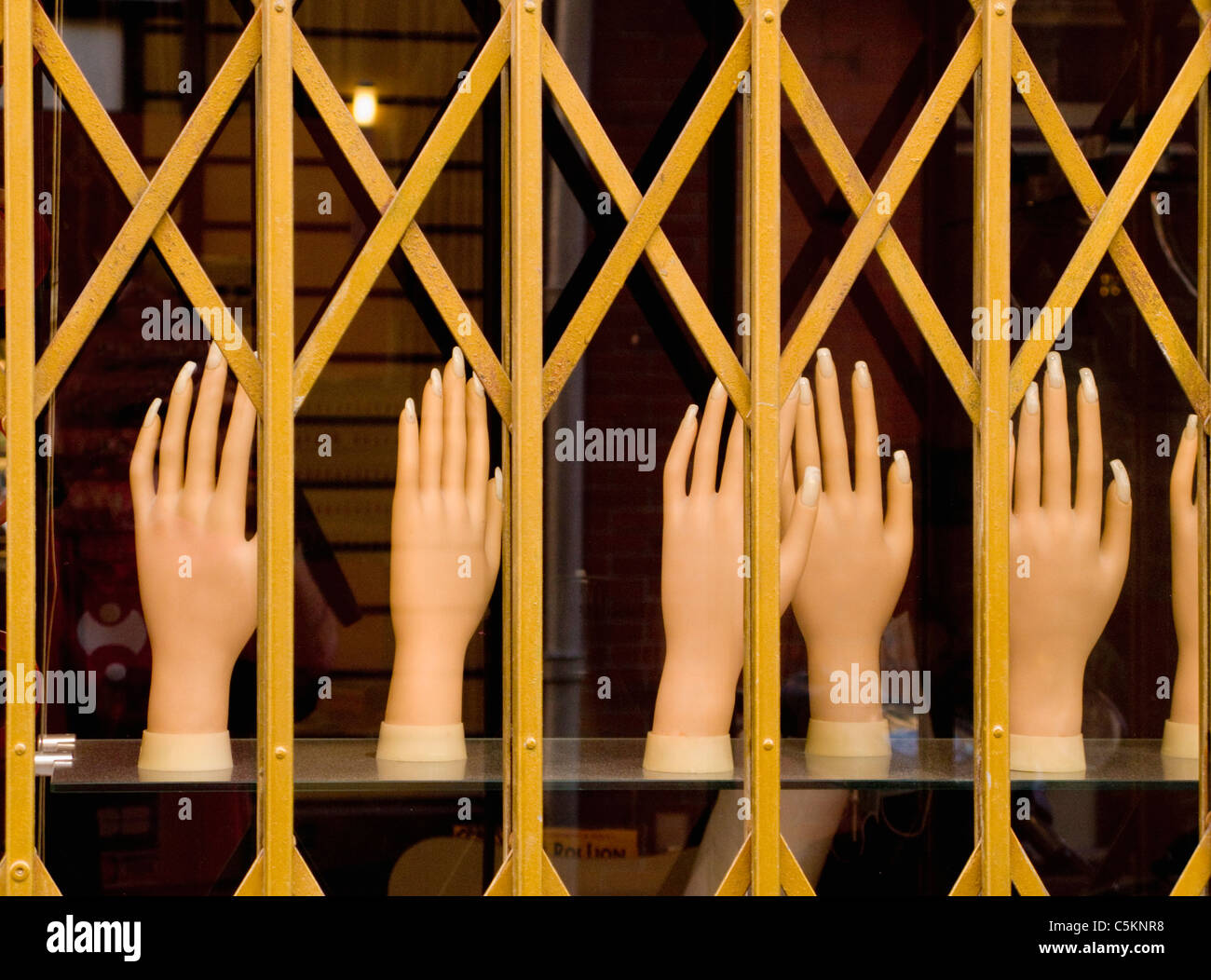 Display of plastic hands in window of a manicurist shop, seen through window grille, Nice, France Stock Photo