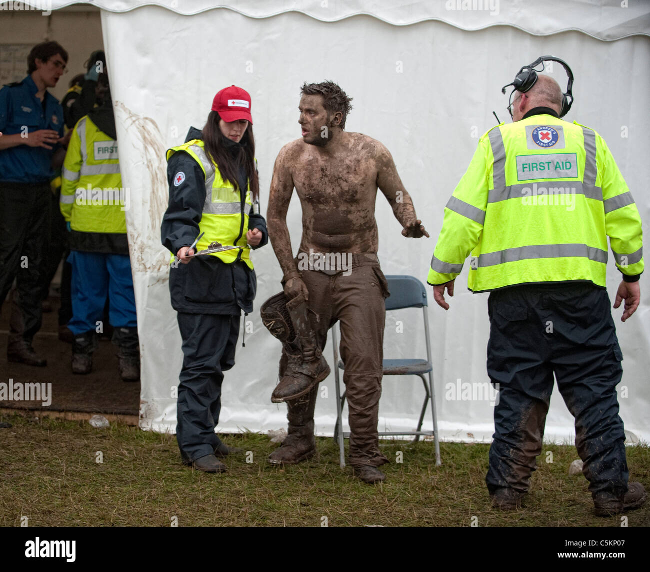 Music fan at festival covered in mud gets treatment from medical staff at the first aid station. Stock Photo