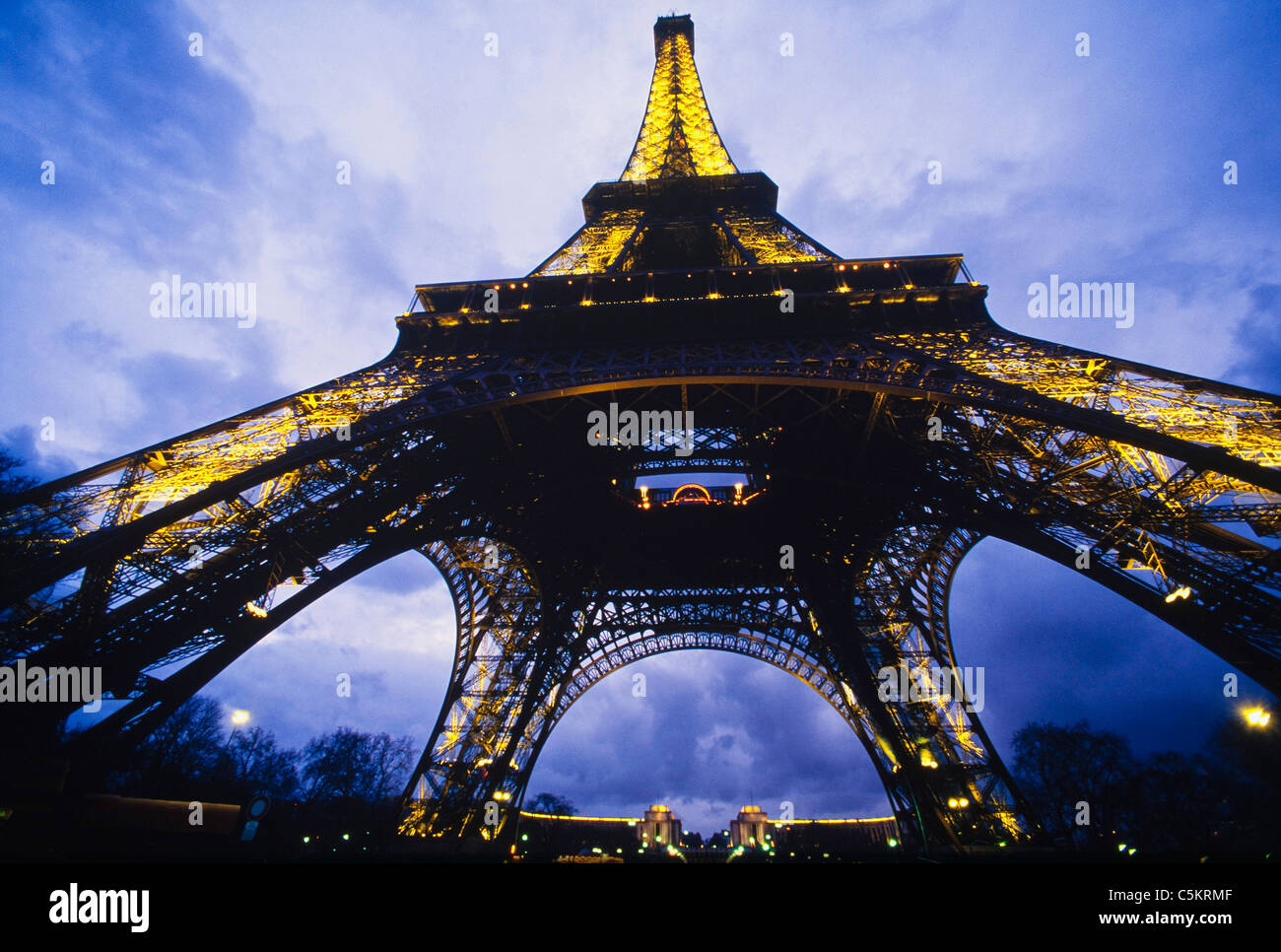 Eiffel Tower in Paris France lit up at dusk against a cloudy sky on ...