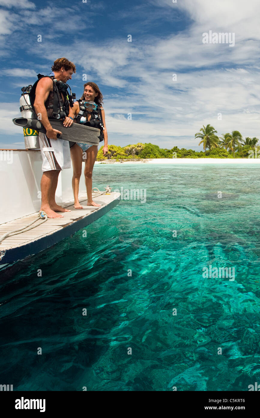 Scuba divers preparing to jump into water from the back of a dive boat. Stock Photo