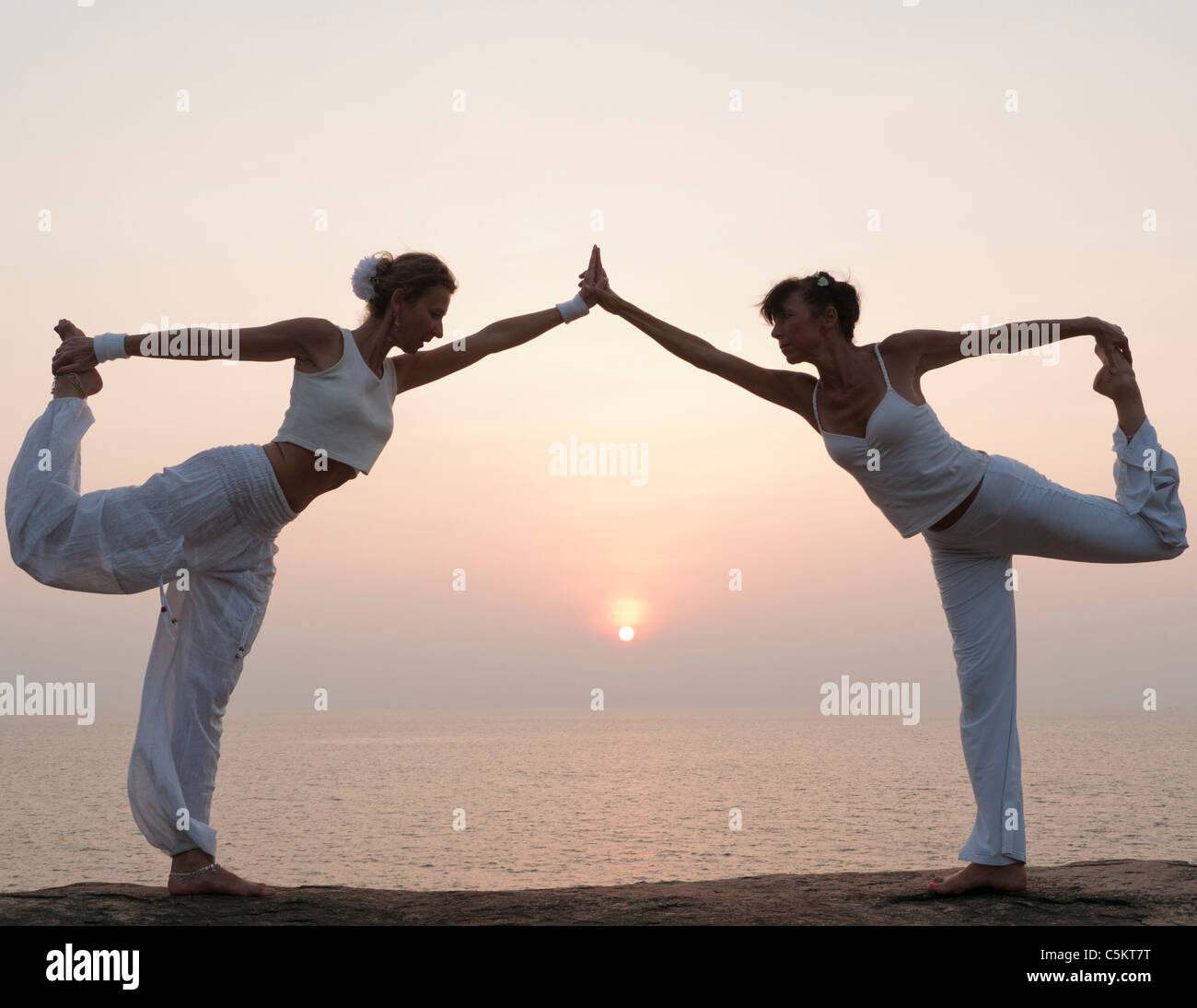 Two women making parter yoga at sunset Stock Photo