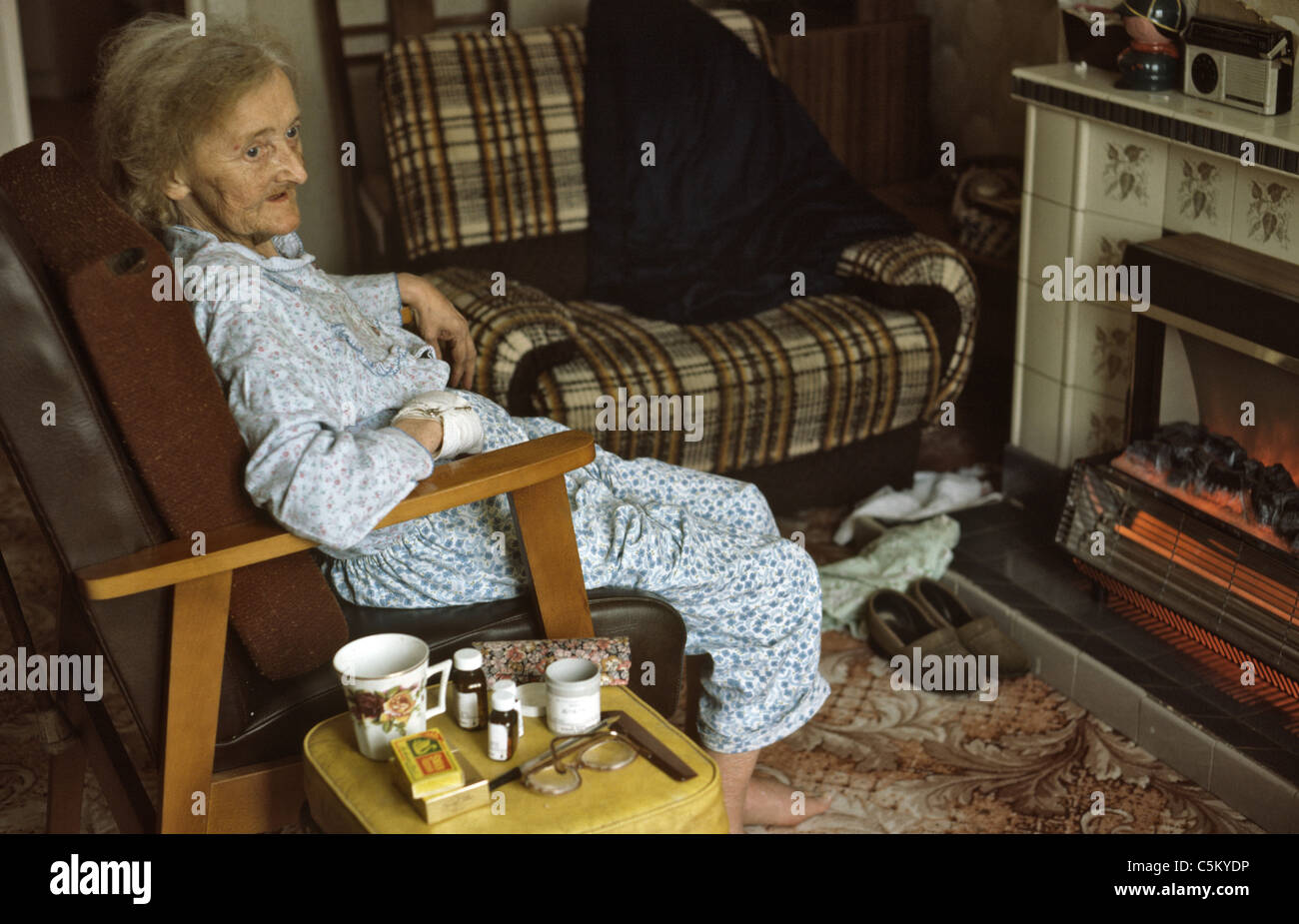 very old frail woman seated in front of electric fire Stock Photo Alamy