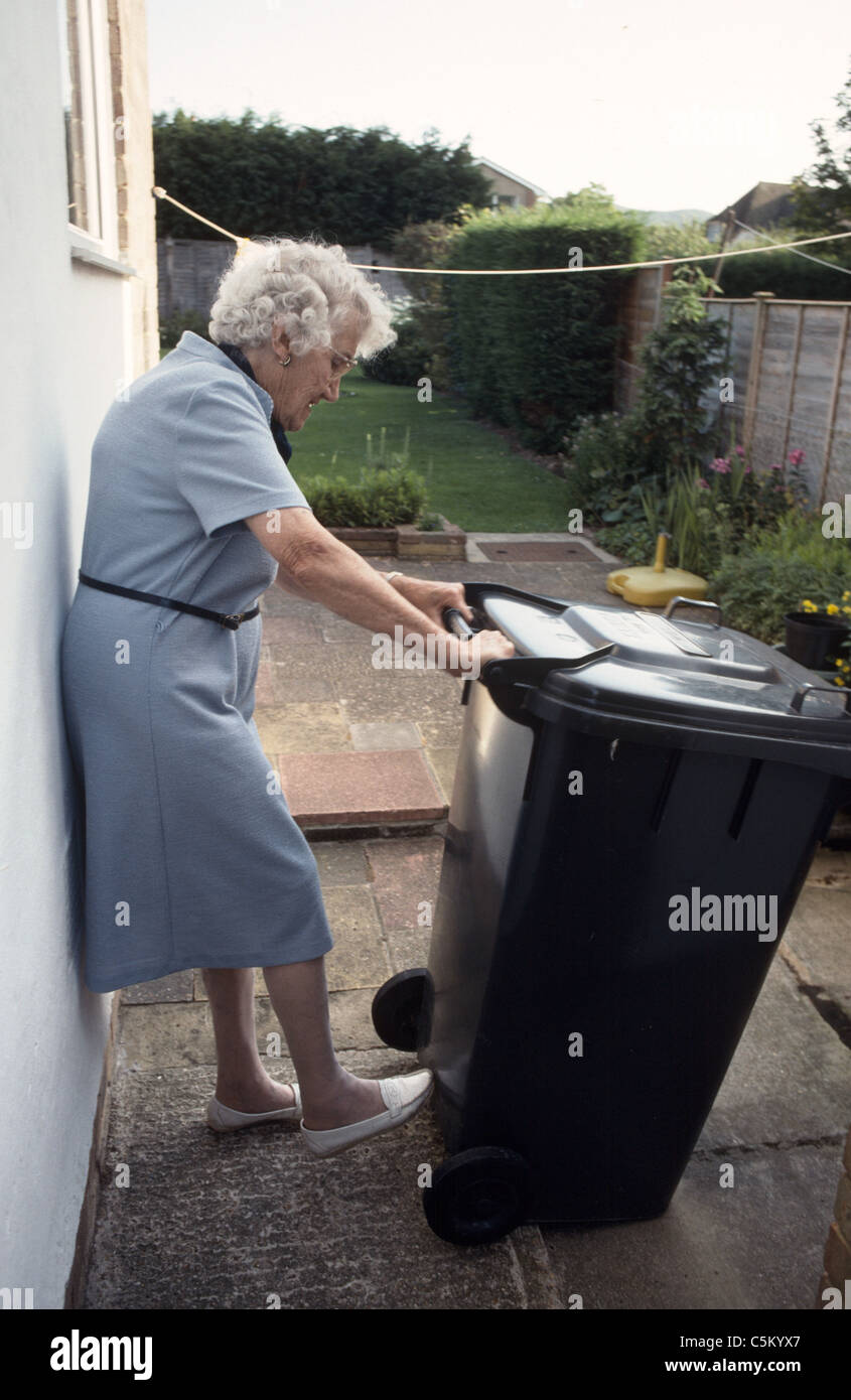 elderly woman moving wheelie bin Stock Photo Alamy