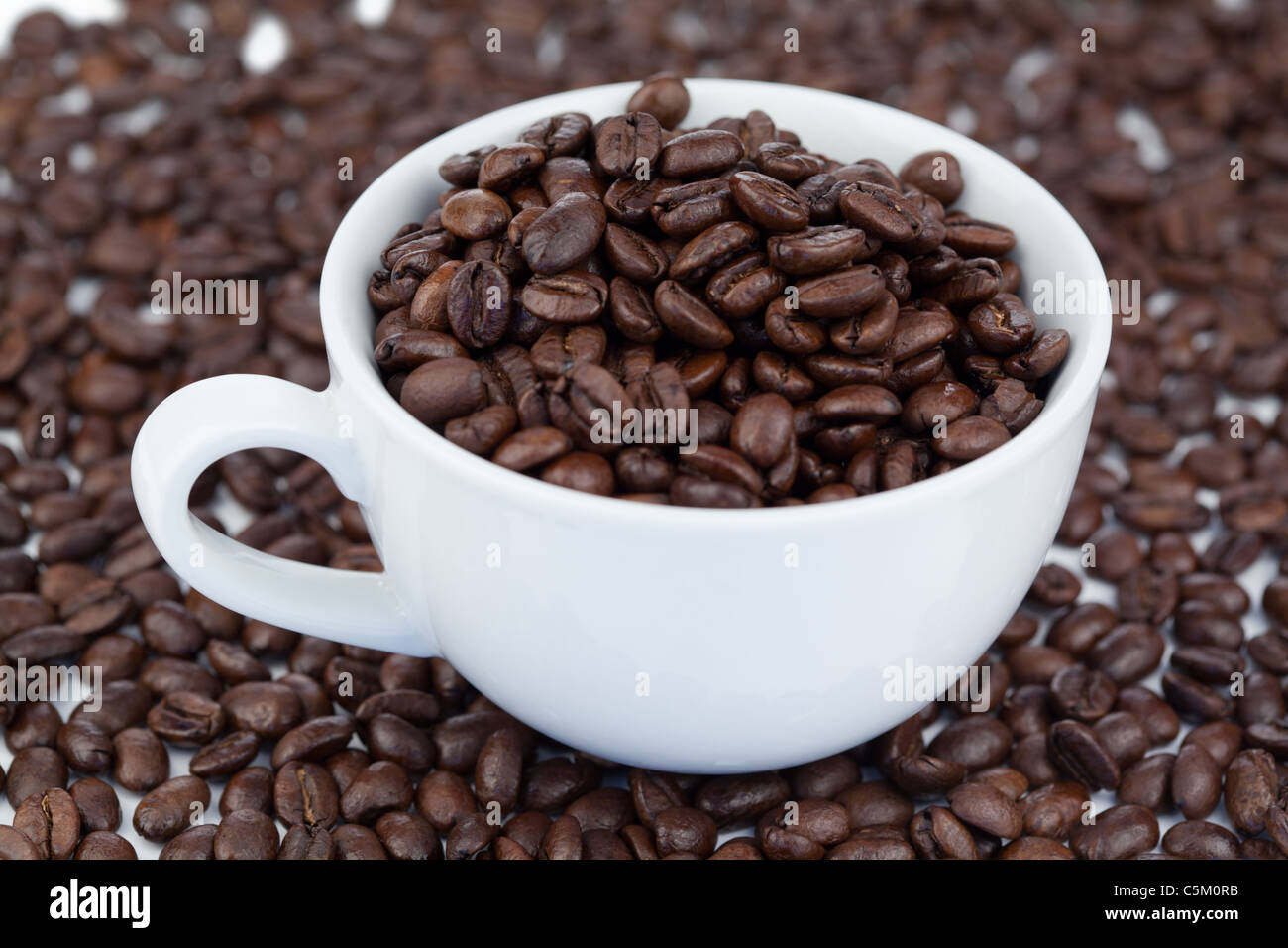 Small white cup of coffee beans Stock Photo