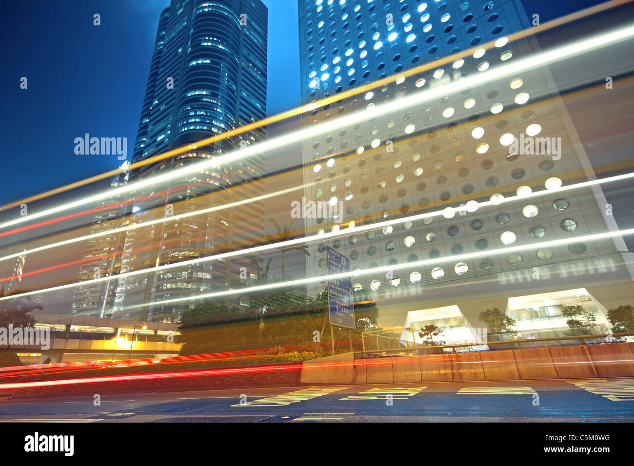 traffic light trails in the street by modern building Stock Photo